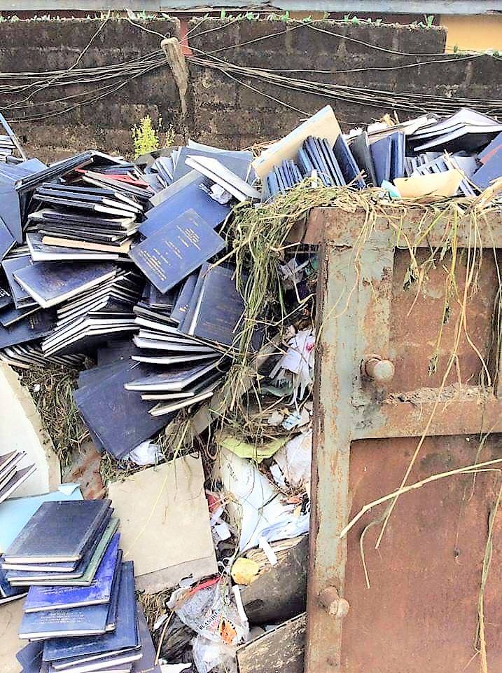 Stacks of abandoned student project reports dumped in a rubbish heap, showing burnt and discarded academic works in a Nigerian university.